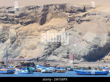 Fishing boats moored off the Paracas National Reserve. The reddish desert landscape that runs along the Pacific coast of Peru south of Paracas is in t Stock Photo