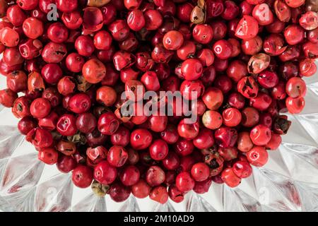 Red peppercorns in a glass bowl on a white background. Top view. Macro shot. Stock Photo