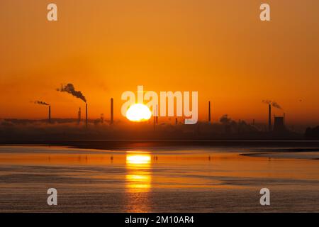 Stanlow Oil Refinery, Ellesmere Port, England, UK. 9th Dec 2022. The sun rises this Friday morning over the refinery, during the continued spell of harsh cold weather, a time when many are struggling with rising energy bills and costs of living. Credit: Callum Fraser/Alamy Live News Stock Photo
