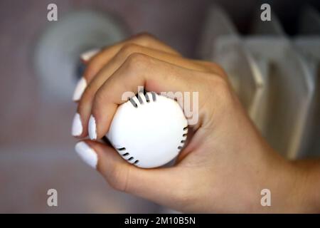 Hand regulating the white Thermostatic Valve for setting the temperature of the radiators for energy saving Stock Photo