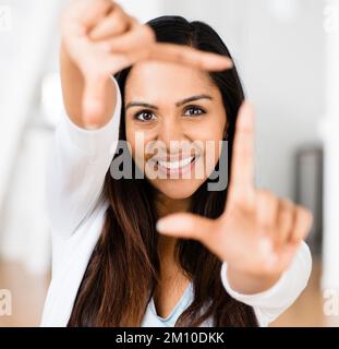 Frame up for the perfect shot. a young indian woman framing her face with her fingers. Stock Photo