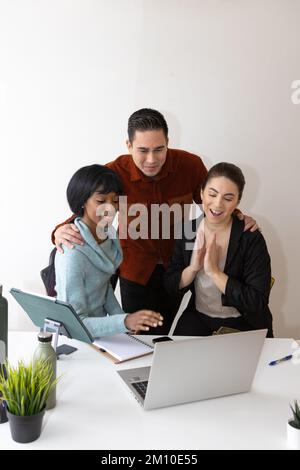 happy boss congratulating the work done by employees, office desk with laptop and tablet Stock Photo