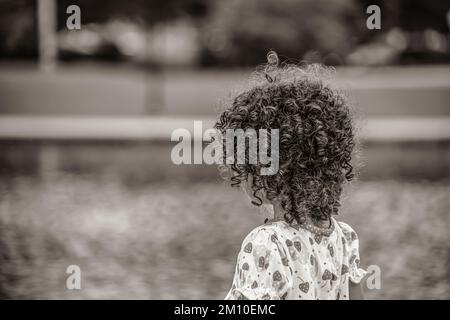 A grayscale shot of little girl with curly hair Stock Photo
