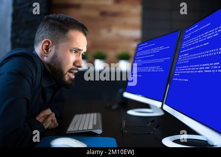 Worried Man At Computer With System Failure Screen At The Workplace Stock Photo