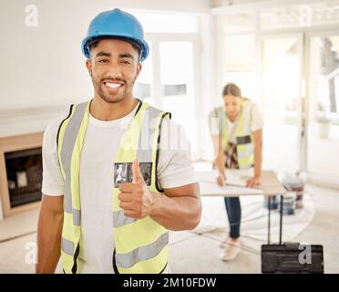 Everythings all going to plan over here. a handsome young construction worker standing inside and making a thumbs up gesture. Stock Photo