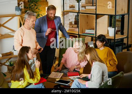 Group of employees, men and women, having professional meeting, discussing company analytics at the office, indoors. Concept of business Stock Photo