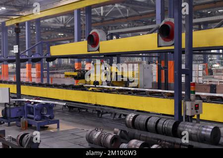 Heavy Industry Engineering Factory Interior with Industrial Worker Using Angle Grinder and Cutting a Metal Tube. Contractor in Safety Uniform and Hard Hat Manufacturing Metal Structures. High quality photo Stock Photo