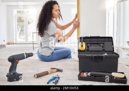 Its time for a home update. a woman using a spirit level while renovating a house. Stock Photo