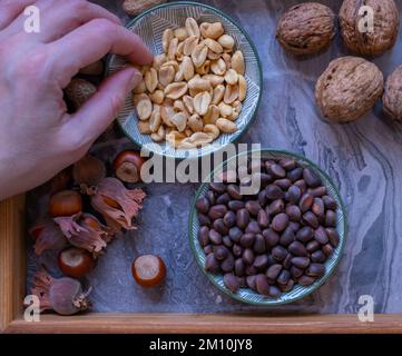 A variety of nuts in bowls from top view. Walnuts, hazelnut, peanut and pine nuts, mix selection. Healthy fitness super food Stock Photo