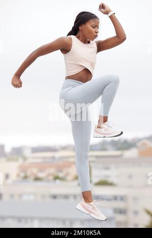 Black woman, jump and fitness while workout, exercise and training in Brazil, city and body warm up for health and wellness. Young female athlete Stock Photo