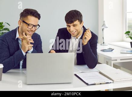 Two happy successful business people using laptop computer while working in the office Stock Photo
