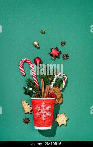 Festive red paper cup with decorations on green background. Merry Christmas and Happy New Year concept Stock Photo