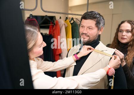 Workers in a sewing workshop take accurate measurements Stock Photo
