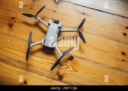 A top view of a small gray drone placed on a wooden background Stock Photo