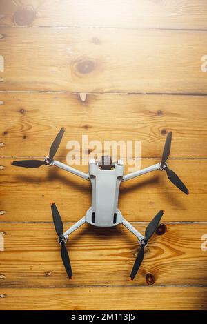 A vertical shot of a small size drone placed on a wooden background Stock Photo