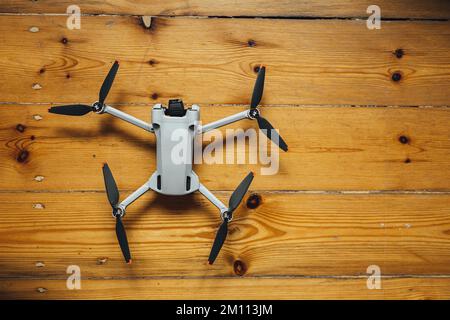 A top view of a small-sized, gray drone placed on wooden background Stock Photo