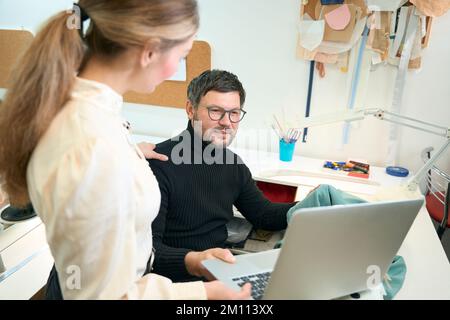 Woman manager with laptop put her hand on shoulder man designer Stock Photo