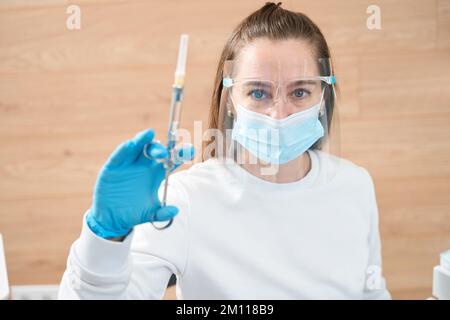 Blue-eyed female doctor holds syringe with medicine in her hands Stock Photo