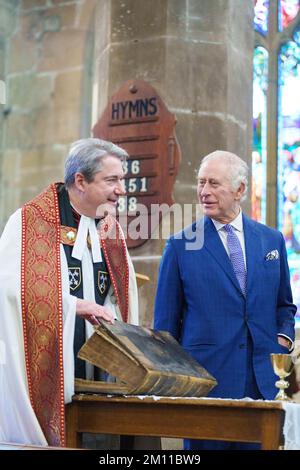 King Charles III is shown a first edition King James Bible and a rare early 14th century chalice by the Rev'd Canon Dr Jason Bray following a celebration at St Giles' Church to mark Wrexham becoming a City. Picture date: Friday December 9, 2022. Stock Photo