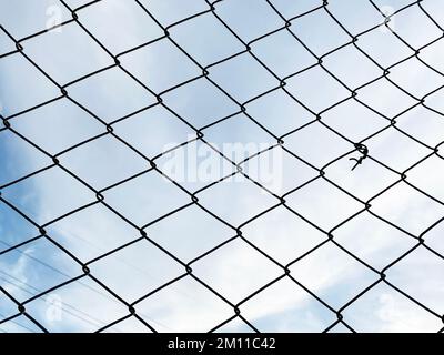 metal mesh fence. Grid net fencing wire against cloudy sky. selective focus Stock Photo