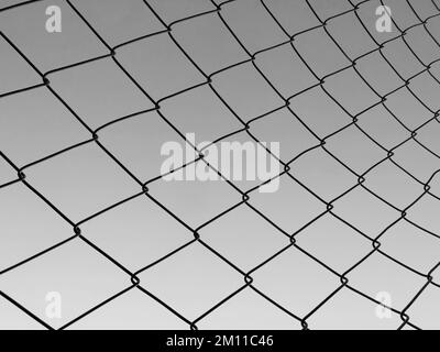 metal mesh fence. Grid net fencing wire against gray sky Stock Photo