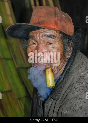 Ziro plateau, Arunachal Pradesh, India - 02 24 2009 : Portrait of old Apatani tribal man smoking bamboo pipe at night Stock Photo