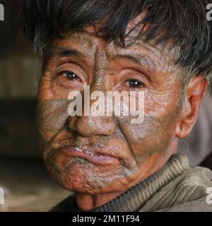Mon district, Nagaland, India - 03 02 2009 : Closeup indoor portrait of old Naga Konyak tribe head hunter warrior with traditional facial tattoo Stock Photo
