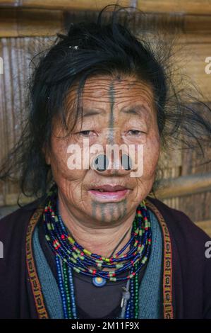 Ziro, Arunachal Pradesh, India - 11 13 2010 : Portrait of old Apatani tribal woman with facial tattoo and nose plugs wearing traditional necklace Stock Photo