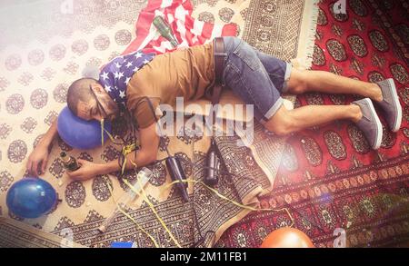Party, drunk and sleeping man after new years, social or drinking holiday event on a home carpet. Alcohol, celebrate and hangover of a tired person Stock Photo