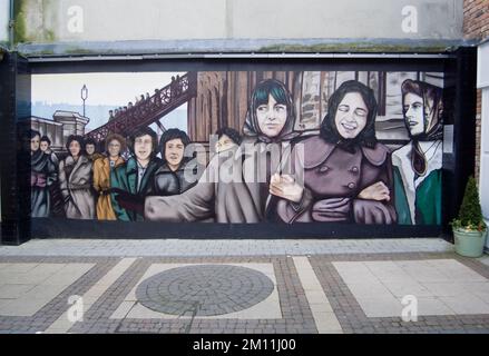 Ireland, North, Derry City, Murals depicting the original Derry Girls who worked in shirt making factories in The Craft Village within the old city walls. Stock Photo