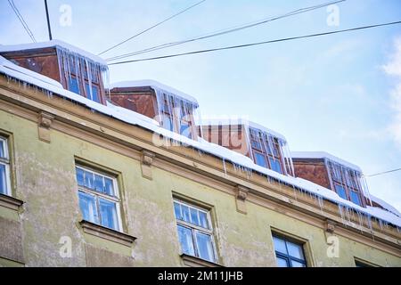 Large icicles hanging on the roof of the house in winter time Stock Photo