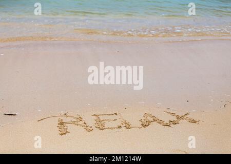 Relax - as a message written with a finger in the sand on a beach with waves and blue ocean at Mauritius Island, Africa, top view, nobody Stock Photo