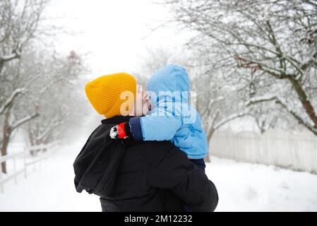 Dad holds his son in his arms in winter. Dad and his son. Dad and his baby. Winter fun. The happy childhood of a young child Stock Photo