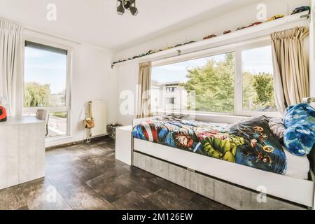 a kid's room with a bed, desk and window looking out onto the street in front of the house Stock Photo