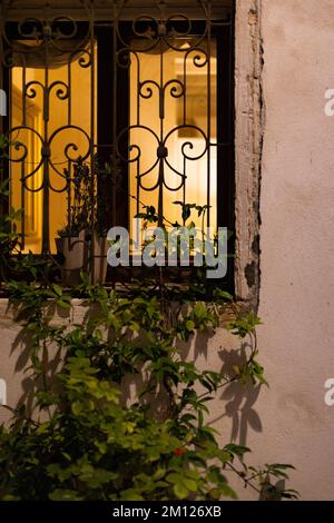 Detail of illuminated window with window grille in the old town of Venice Stock Photo