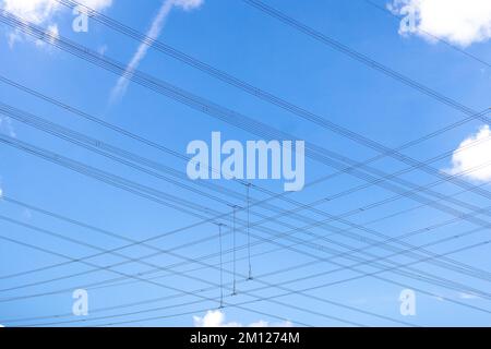 Power cables from overhead power lines against blue sky in Germany Stock Photo