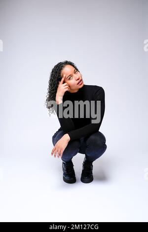 Young Multiracial Woman Squatting Facing Camera | Isolated on white background Stock Photo