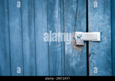 Old padlock and blue boards keep door locked. Stock Photo