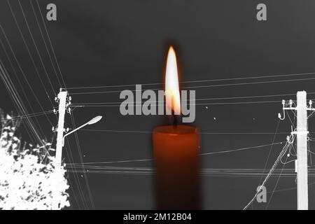 Blackout, power grid overloaded. Blackout concept. Earth hour. Burning flame candle and power lines on background. Energy crisis. Dark night. Candle Stock Photo