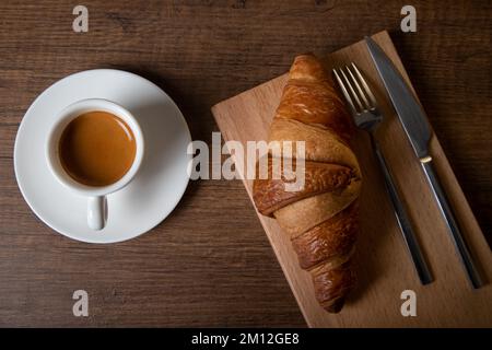 Croissant with espresso in white cup on wooden table Stock Photo