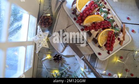 Christmas home made cinnamon cake with fruits and spekulatius cookies cream by the window on a winter interior scene. Stock Photo