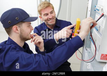 apprentice holding multimeter probes on an electrical panel Stock Photo