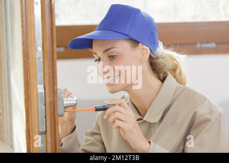 happy female builder using a screwdriver on a door Stock Photo