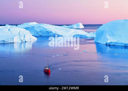 Red boat with tourists in front of icebergs at blue hour, Icefjord, UNESCO World Heritage Site, Disko Bay, Ilulissat, West Greenland, Greenland, North Stock Photo