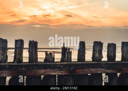 Sunset on the northern beach of the North Sea island of Norderney, blurred groynes in the foreground Stock Photo
