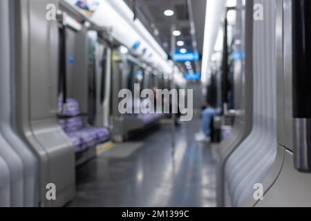 Blurred empty interior of a modern metro train, inside of an underground subway train with two unrecognizable people. Public transportation concept. Stock Photo