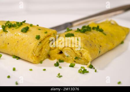 French Chives Omelette, Runny or Baveuse Eggs with Green Herbs on a White Plate Stock Photo