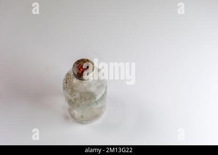 One dirty clear glass medical vaccine bottle, aged and patina on a white background.  Empty and covered with dirt and rust. Stock Photo