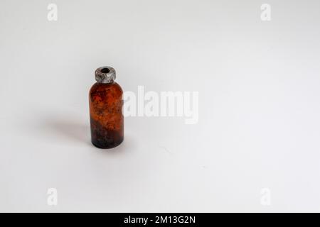 One small amber glass vaccine bottle, aged and patina on a white background.  Empty and covered with dirt and rust. Stock Photo
