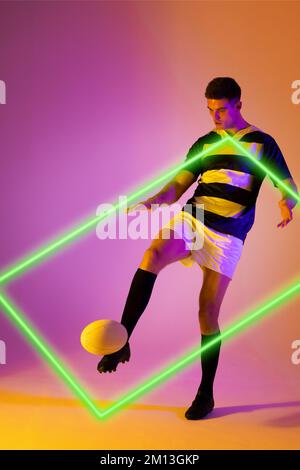 Caucasian male rugby player kicking ball by illuminated rectangle over gradient background Stock Photo